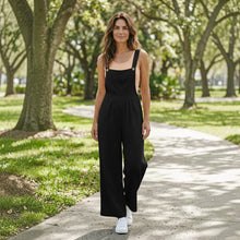 Load image into Gallery viewer, Model wearing Aurora Boutique Miami black linen wide leg jumpsuit with a peach tank top in a park setting