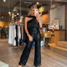 Load image into Gallery viewer, Aurora Boutique Miami model wearing a black one-shoulder jumpsuit with a satin bodice and sequin wide-leg pants