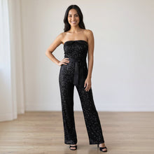 Load image into Gallery viewer, Model wearing Aurora Boutique Miami black sequin tube jumpsuit with a satin belt in a bright studio setting