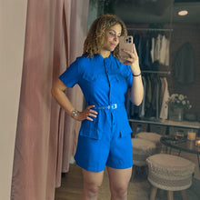 Load image into Gallery viewer, Model wearing a bright blue Aurora Boutique Miami button-up romper with front pockets and a matching waist belt.