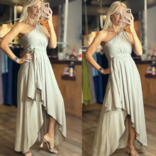 Load image into Gallery viewer, Aurora Boutique Miami cocoa one-shoulder flowy dress with a high-low hemline worn by a blonde model in a boutique