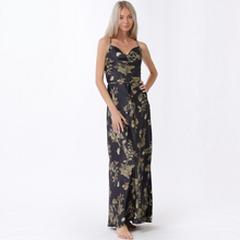 Load image into Gallery viewer, Model wearing Aurora Boutique Miami Candelaria maxi dress with black and gold floral print, cowl neck, and waist belt.