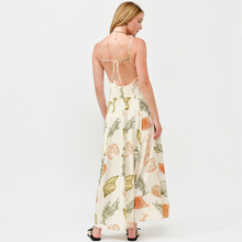 Load image into Gallery viewer, Model wearing Aurora Boutique Miami Juniper open back maxi dress with cream base and orange and green shell print