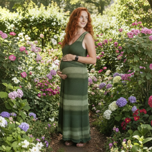 Load image into Gallery viewer, Aurora Boutique Miami Sueli crochet dress in green ombré worn by a pregnant woman in a lush blooming garden