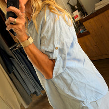 Load image into Gallery viewer, Aurora Boutique Miami Valeria light blue linen shirt with roll-tab sleeves worn by a woman in a boutique setting
