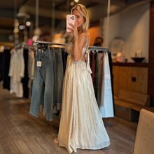 Load image into Gallery viewer, Aurora Boutique Miami Anori maxi dress in metallic gold with an open bust and tie-back detail worn by a model
