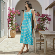 Load image into Gallery viewer, Model wearing Aurora Boutique Miami Aveline maxi dress in bright blue with white floral pattern on a sunny patio.
