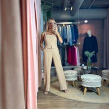 Load image into Gallery viewer, Model wearing a beige Aurora Boutique Miami Lucy viscose jumpsuit with a square neckline in a boutique setting.
