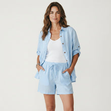 Load image into Gallery viewer, Model wearing Aurora Boutique Miami light blue linen shirt with matching shorts and white tank top
