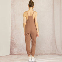 Load image into Gallery viewer, Back view of a model wearing an Aurora Boutique Miami brown cable knit jumpsuit with thin straps and tapered legs.
