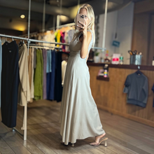 Load image into Gallery viewer, Aurora Boutique Miami cocoa one-shoulder flowy maxi dress worn by a blonde model in a boutique setting
