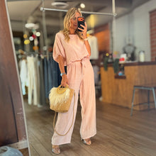 Load image into Gallery viewer, Aurora Boutique Miami Delmar linen blouse in soft pink paired with matching wide-leg trousers and a straw handbag.
