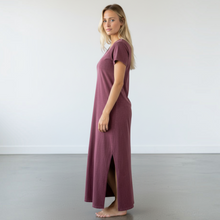 Load image into Gallery viewer, Model wearing a maroon Aurora Boutique Miami Lia cotton t-shirt dress with side slits in a minimalist studio setting.
