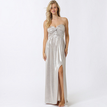 Load image into Gallery viewer, Model wearing a metallic silver Aurora Boutique Miami Fortul maxi dress with a twist front bust and side leg slit.
