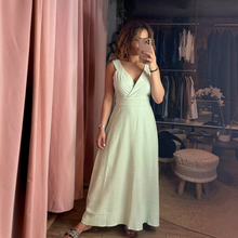 Load image into Gallery viewer, Model wearing an Aurora Boutique Miami mint green tied maxi dress with a V-neckline in a boutique setting
