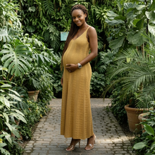 Load image into Gallery viewer, Aurora Boutique Miami Lais crochet maxi dress in mustard yellow worn by a pregnant woman in a lush greenhouse
