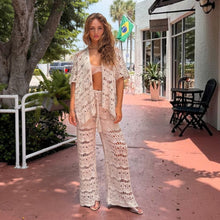Load image into Gallery viewer, Model wearing Aurora Boutique Miami Nicole 3-piece beige crochet set with open shirt and wide-leg pants outdoors
