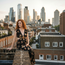Load image into Gallery viewer, Aurora Boutique Miami Olaya floral maxi dress with ruffle sleeves and cut-out waist worn by a model on a city rooftop
