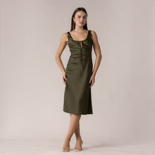 Load image into Gallery viewer, Model wearing an Aurora Boutique Miami olive green satin midi dress with a front tie detail and scoop neckline.
