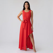 Load image into Gallery viewer, Model wearing a red Aurora Boutique Miami Montreal dress with a high-low hem and waist tie on a white background
