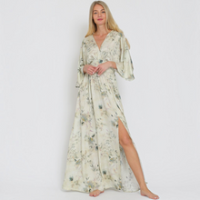Load image into Gallery viewer, Model wearing an Aurora Boutique Miami Saravena floral maxi dress with kimono sleeves and a side slit on white background
