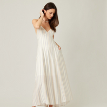 Load image into Gallery viewer, Model wearing Aurora Boutique Miami Ivetta open back midi dress in cream with blue and tan vertical stripes
