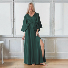 Load image into Gallery viewer, Model wearing an Aurora Boutique Miami Tamara maxi dress in dark green with kimono sleeves and a side leg slit
