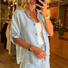 Load image into Gallery viewer, Aurora Boutique Miami Valeria light blue linen shirt worn over a white tank top in a boutique setting
