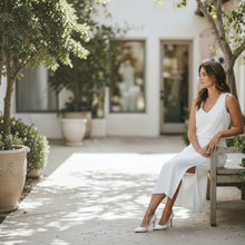 Load image into Gallery viewer, Model wearing a white Aurora Boutique Miami Whitley skirt set with a sleeveless top and side-slit midi skirt outdoors.
